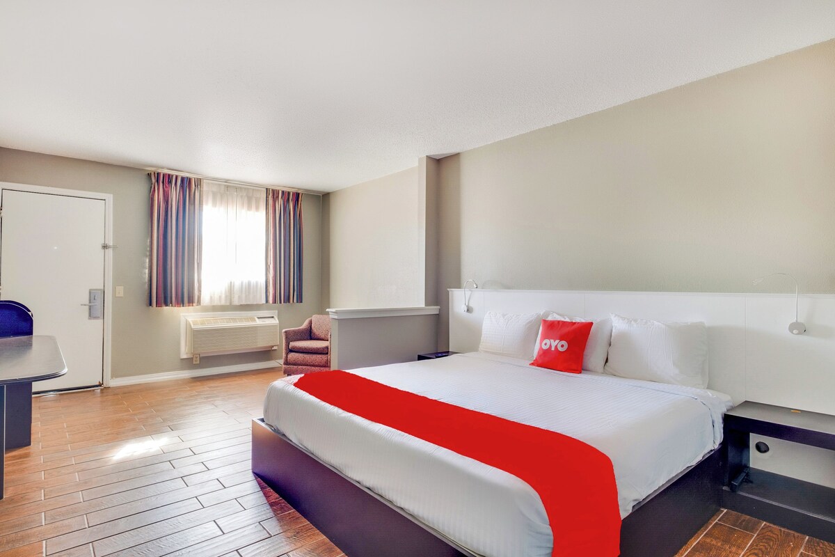Una habitación de hotel con una cama grande, un escritorio, una silla y una ventana con cortinas.