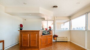 A reception area with a wooden counter, potted plants, and a view through a large window. - OYO Hotel Elk City OK Route 66 (Elk City)