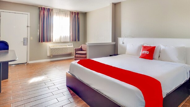 A hotel room with a bed, a desk, a chair, and a window with curtains. - OYO Hotel Elk City OK Route 66 (Elk City)
