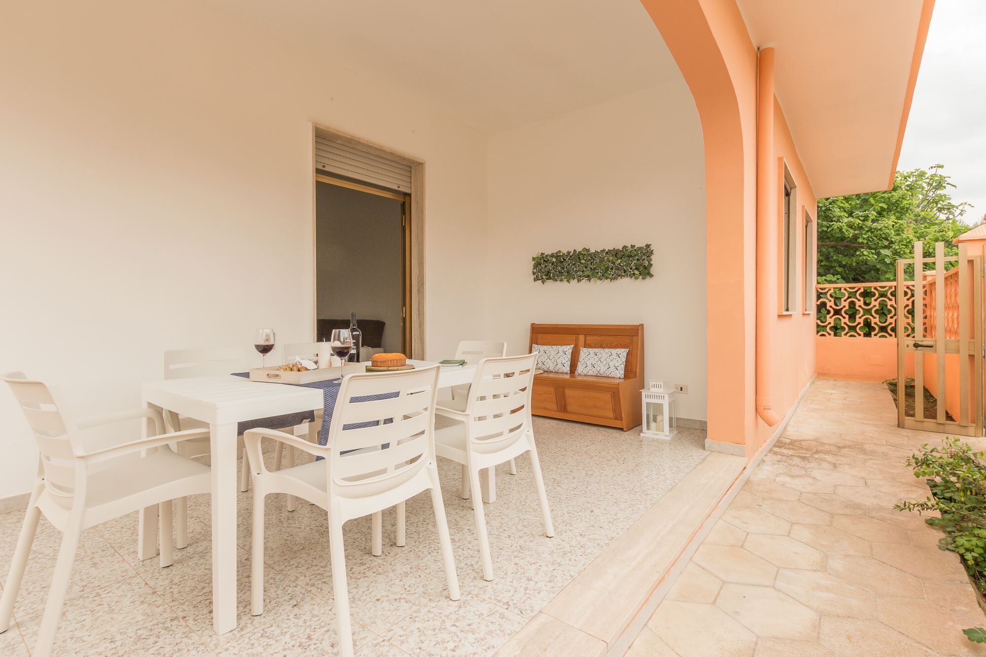 A dining area with a table set for two, a wooden bench, and a small side table with a candle.