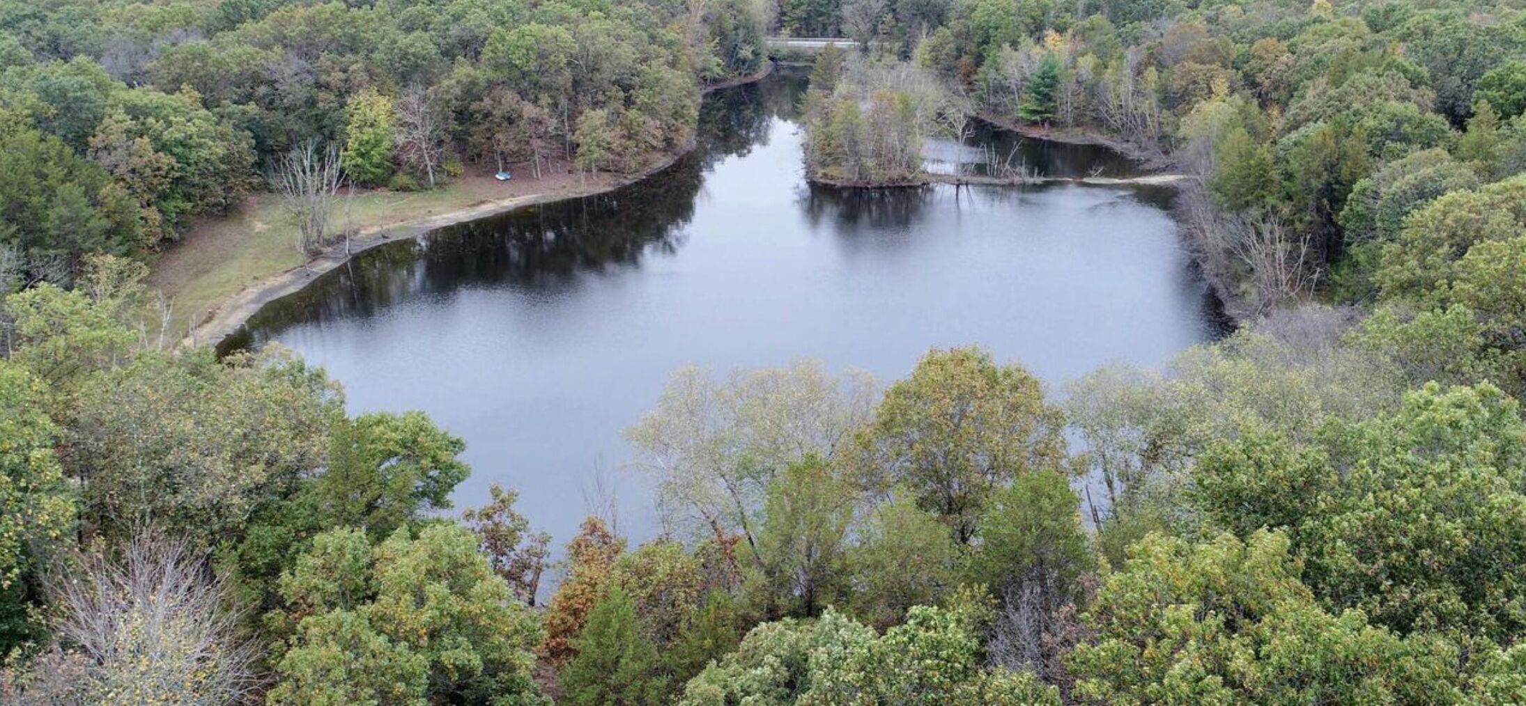 A natural landscape with a lake surrounded by dense forest.