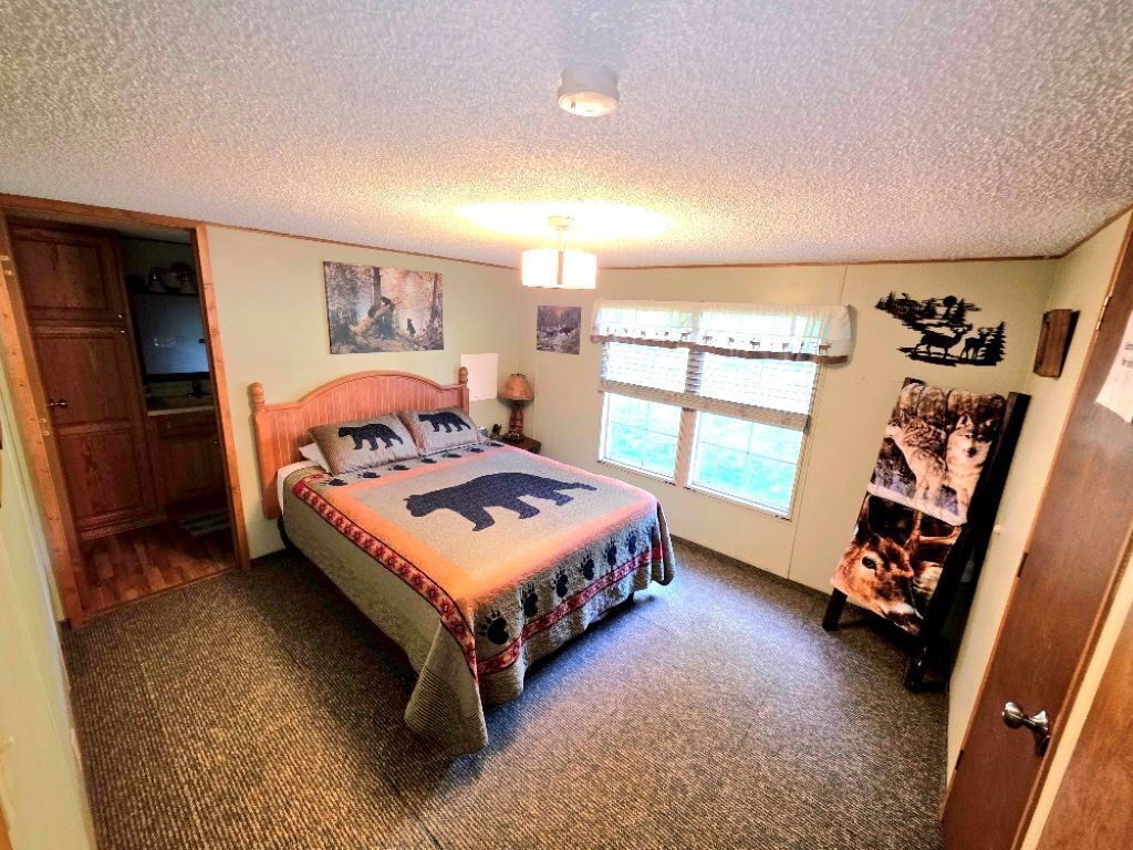 Une chambre à coucher avec un lit, une fenêtre avec des stores, une armoire en bois et un mur décoré de motifs animaliers.