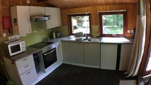 A compact kitchen with a microwave, stove, sink, and cabinets. - Snowdrop 14 Hot Tub (Carmarthen)