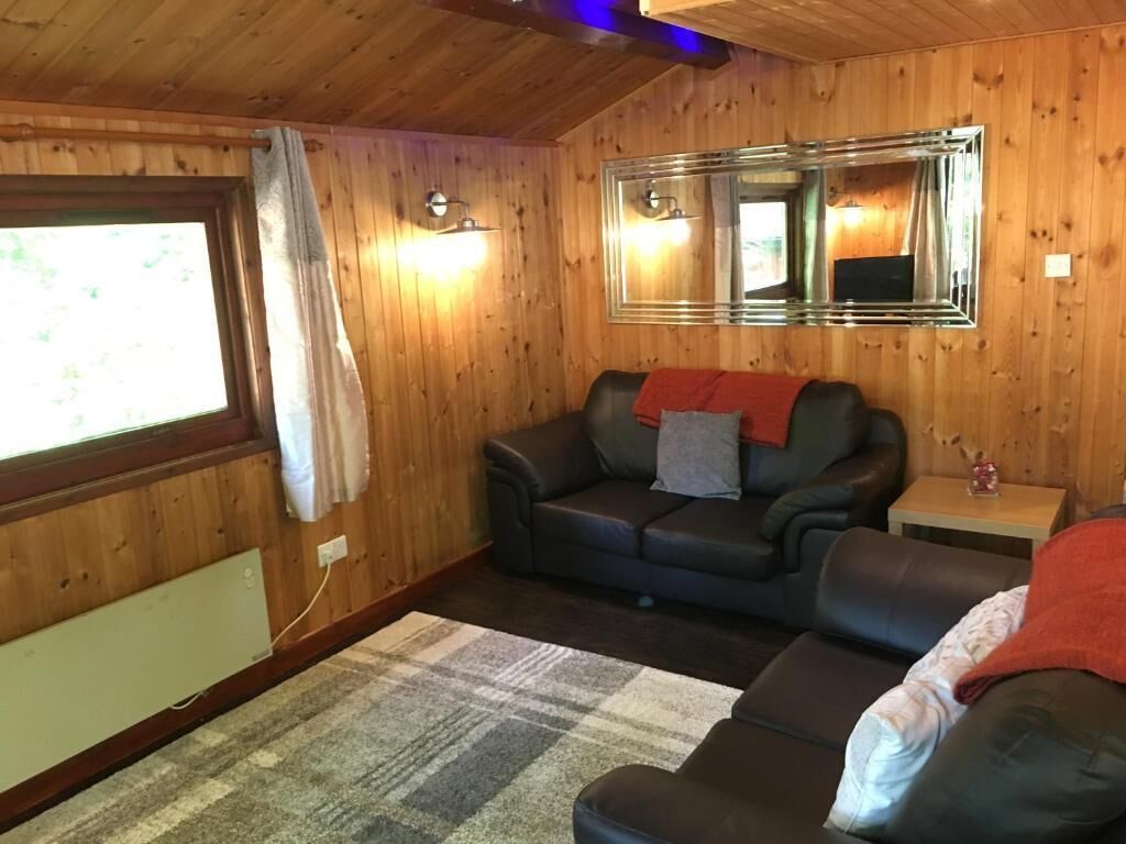 A cozy room with a wooden interior, a large mirror, a leather sofa, and a small table with a lamp.