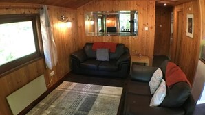 A wooden interior with a sofa, a rug, and a mirror. - Snowdrop 14 Hot Tub (Carmarthen)