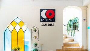 A hotel entrance with a stained glass door, a wall-mounted sign reading "CAPITAL O SAN JOSE", and a staircase leading to an upper floor. - Capital O Hotel San Jose, San Luis PotosÃ­ (San Luis Potosi)