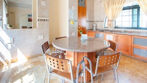 A modern kitchen with a round granite island, wooden cabinets, and a window with curtains. - Capital O Hotel San Jose, San Luis PotosÃ­ (San Luis Potosi)
