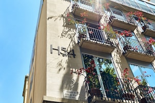 Um edifício com o número 15A na fachada, varandas adornadas com flores vermelhas e uma placa indicando 'Passeig de Joan de Borbo' em Barcelona.