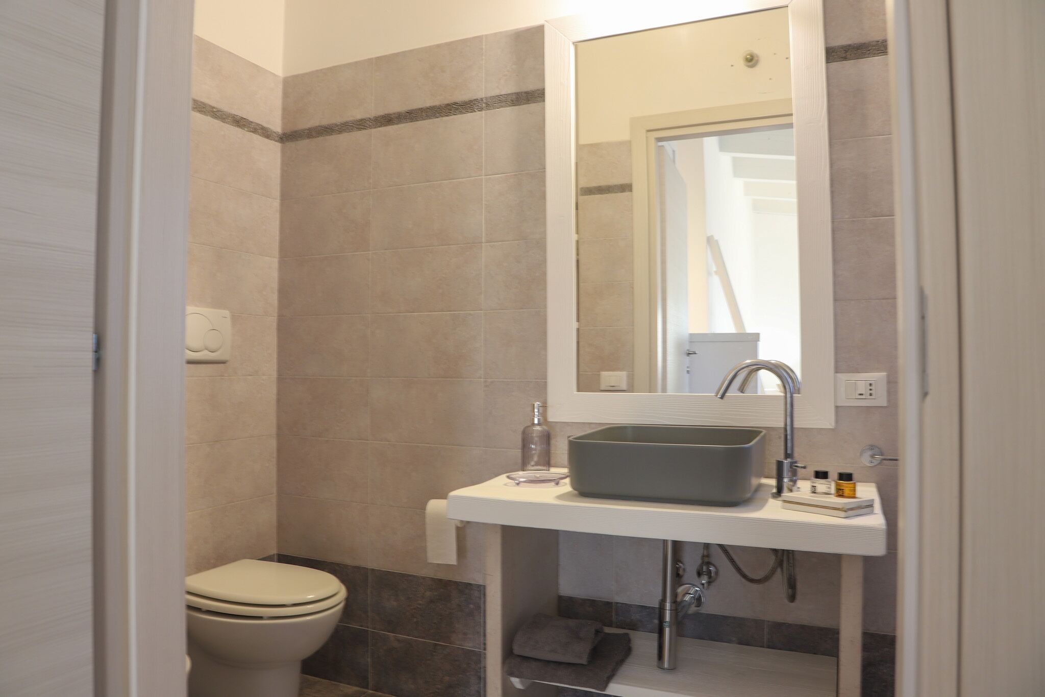 A bathroom with a toilet, a sink with a mirror, and a shower area.