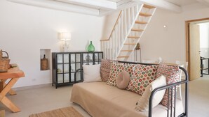 A cozy living room with a sofa, a wooden table, a cabinet with glass doors, and a staircase. - TD Trullo Roverella Charming Trullo with Pool (Castellana Grotte)