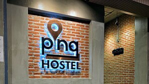 A hostel with a brick wall and a wooden bench in front. - Pinghostel - Adults Only (Chiang Mai)