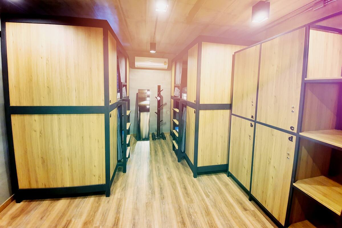 A hallway with wooden lockers and shelves, a radiator, and a ceiling light.