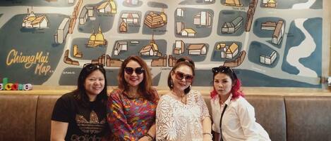 A group of people seated on a couch in front of a wall with a map labeled "Chiang Mai Map."