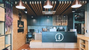 A modern reception area with a wooden desk, a large 'i' logo, and pendant lighting. - Pinghostel - Adults Only (Chiang Mai)