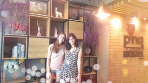 A room with a brick wall, a bookshelf with various items, and a sign for 'png hostel'. - Pinghostel - Adults Only (Chiang Mai)