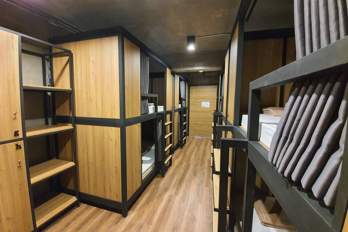 A corridor with bunk beds and wooden shelving units.