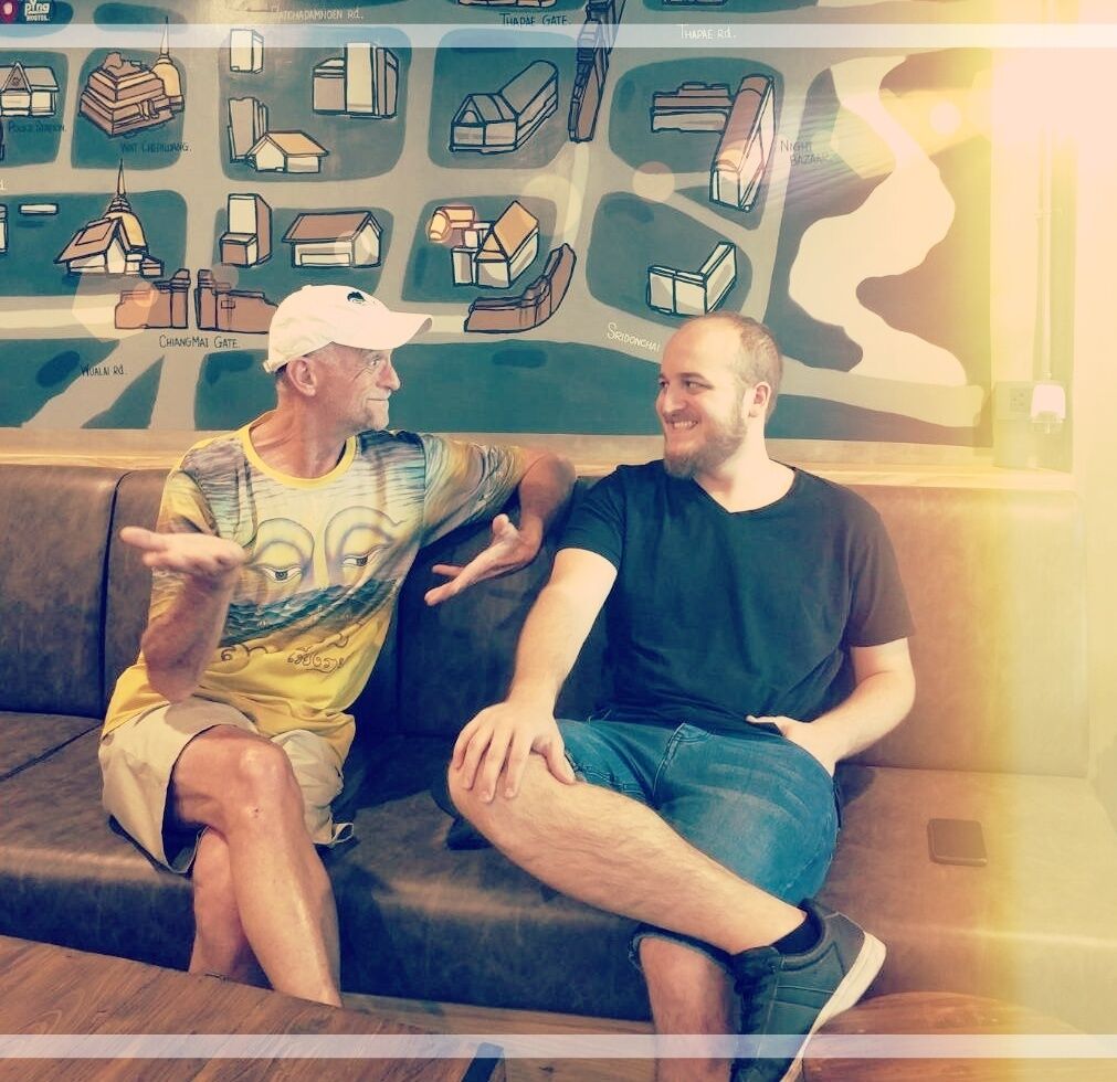 Two people sitting on a couch in a lobby with a map and various icons on the wall.