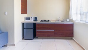 A compact kitchen with a microwave, coffee maker, and gas stove. - Suites del Pozo (San Luis Potosi)