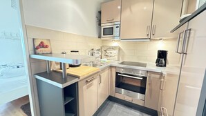 A compact kitchen with a microwave, oven, and coffee maker. - House by the Sea App. 21 (Westerland)