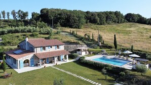 A two-story stone house with a swimming pool, surrounded by a well-maintained lawn and a hilly landscape. - Fantastic new villa near the sea in one of the most beautiful areas of Tuscany  (Pomaia)