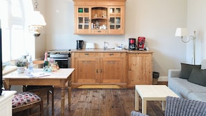 A cozy kitchen with wooden cabinets, a dining table, and a sofa. - Lille Villa App Stars Westerland (Westerland)