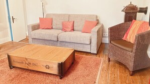 A living room with a sofa, armchair, wooden coffee table, and a rug. - Lille Villa App Moon Westerland (Westerland)