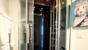 A modern bathroom with a glass-enclosed shower, wooden flooring, and a towel rack. - EO Bungalows – Adults Only (Custer)