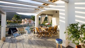 A covered outdoor seating area with a table and chairs, a view of the landscape, and a pergola structure. - Flower house - Charming cottage 500 meters from the beach (Tertenia)