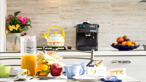 A kitchen with a coffee maker, a fruit bowl, and a pitcher of orange juice on the counter. - Flower house - Charming cottage 500 meters from the beach (Tertenia)