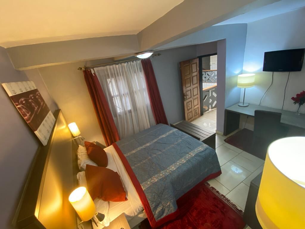 Une chambre à coucher avec un lit, des lampes de chevet, une télévision et un tapis rouge.