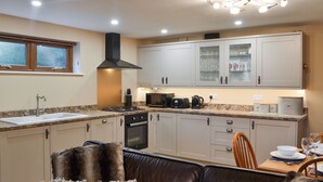 A modern kitchen with a gas stove, oven, and a dining area with a table set for two.