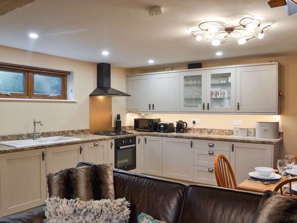A modern kitchen with a gas stove, oven, and a dining area with a table set for two.