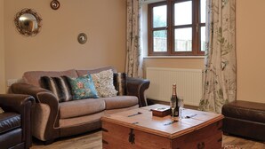 A living room with a brown leather sofa, a wooden coffee table, and a patterned rug.