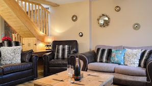 A cozy living room with a wooden chest, leather sofas, and a staircase.