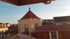 Un edificio con techo de tejas rojas y fachada amarilla, rodeado de otros edificios con techos similares.