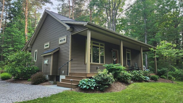 A two-story house with a front porch, surrounded by a well-maintained lawn and dense trees. - Naples Valley Getaway-Private home with hot tub.   (Naples)