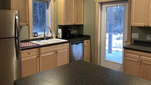 A kitchen with wooden cabinets, a stainless steel refrigerator, a double sink, and a coffee maker. - Naples Valley Getaway-Private home with hot tub.   (Naples)