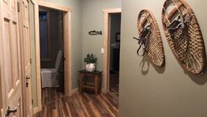 A hallway with wooden flooring, a potted plant on a small table, and a wall-mounted rack. - Naples Valley Getaway-Private home with hot tub.   (Naples)
