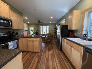 A kitchen with wooden cabinets, a microwave, a refrigerator, and a dining area with a chair and table.