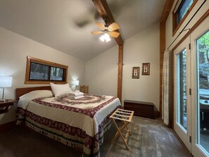 A bedroom with a bed, a ceiling fan, a window, and a nightstand.