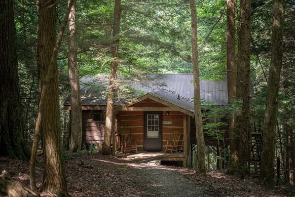 A rustic cabin with a wooden exterior, a front porch, and a door labeled "Over the Hill".