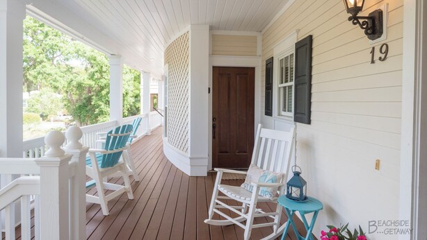 A porch with white railings, two rocking chairs, a small table with a lantern, and a door with the number 19. - Southern Charm, Upscale Home - 19 Egret (Hilton Head Island)