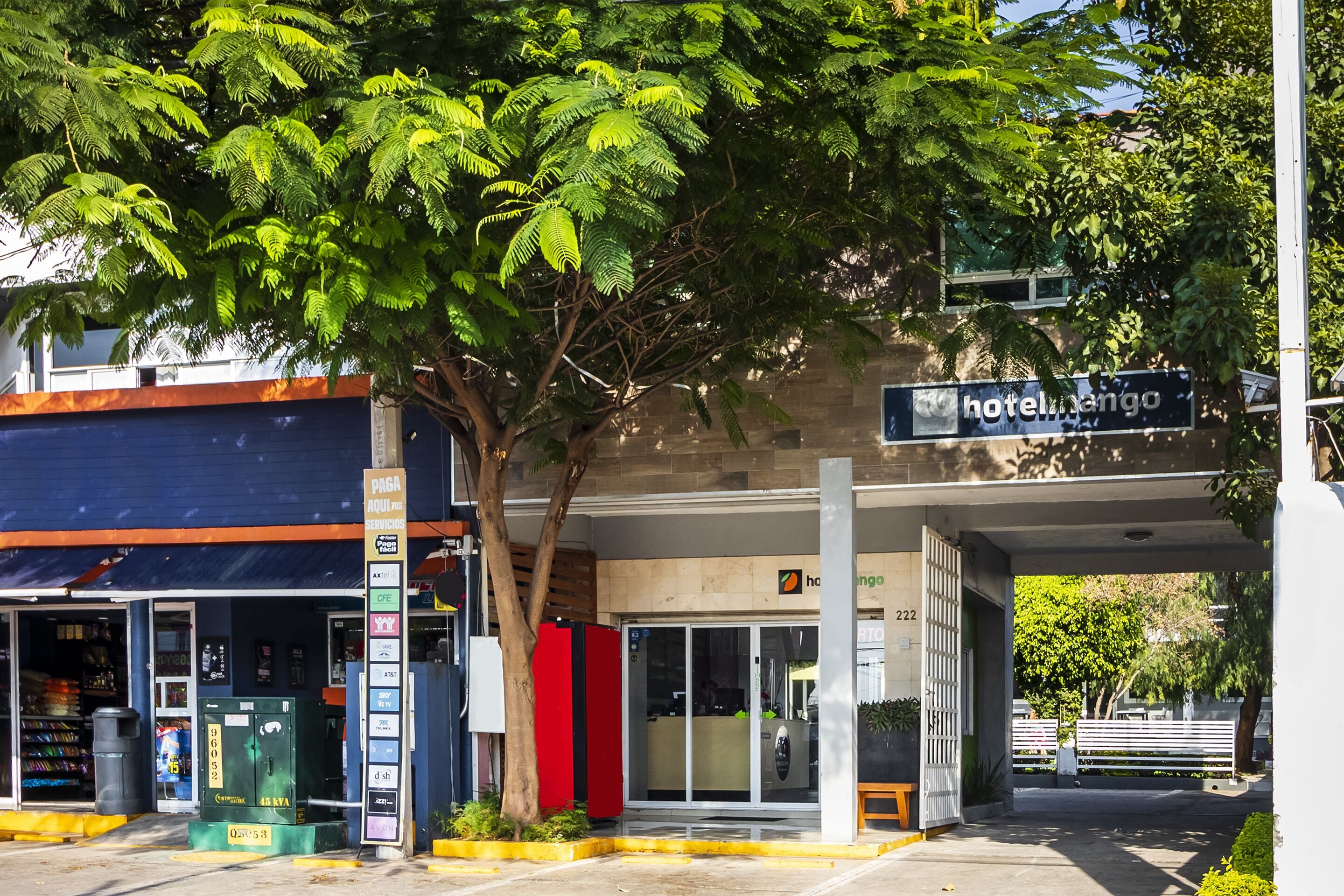 A hotel entrance with a sign reading "hotel mango," a reception desk, and a vending machine.