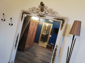 Espejo con marco ornamentado, armario de madera y un baño con lavabo y espejo.