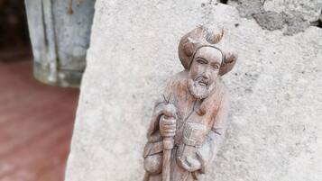 A stone statue of a figure holding a staff, mounted on a concrete structure.