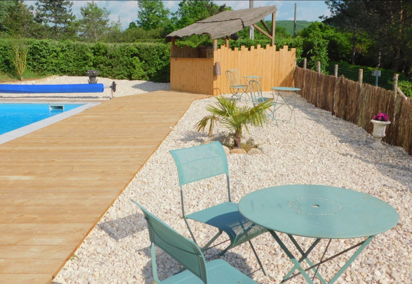 Une terrasse en bois avec une piscine, une petite construction en bois et un espace salon extérieur.