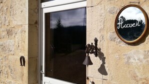 A stone building with a white door, a bell, and a sign that reads "Accueil". - Le Puits de Garival (Tour-de-Faure)