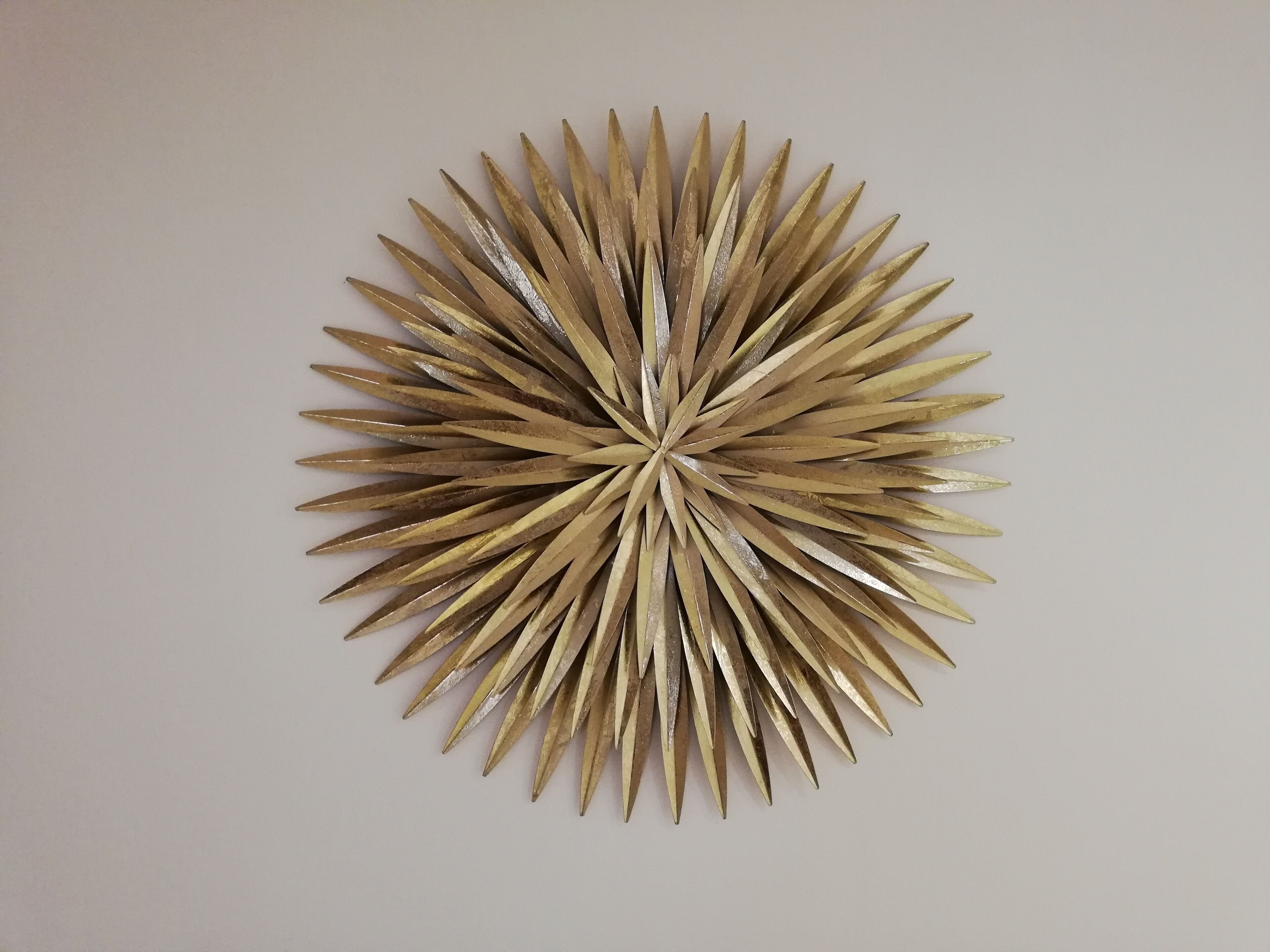 Una pieza decorativa montada en la pared con un diseño radial de elementos metálicos.
