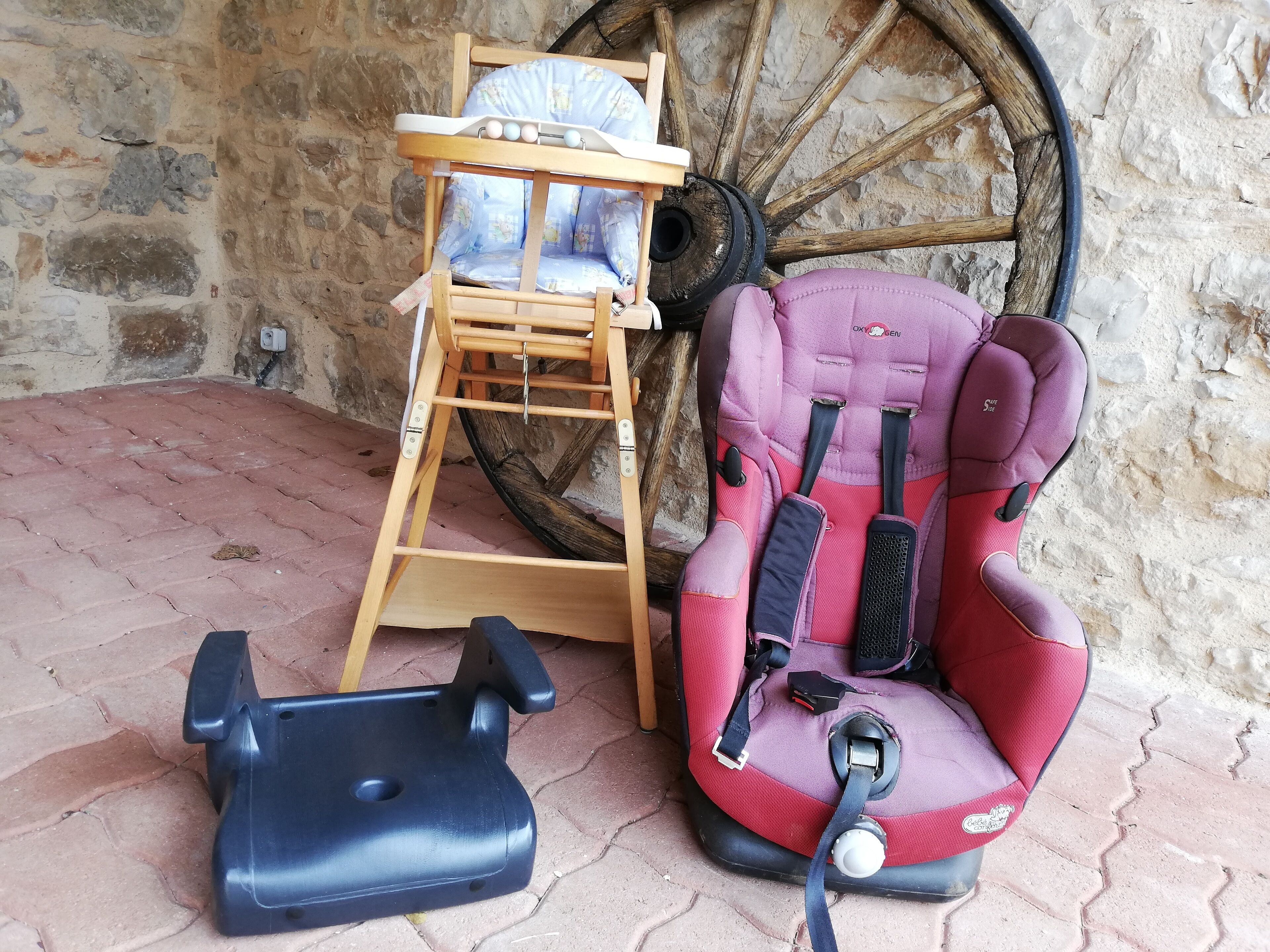 A baby changing station with a wooden seat and a baby seat with a safety harness.