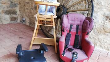 A baby changing station with a wooden seat and a baby seat with a safety harness.